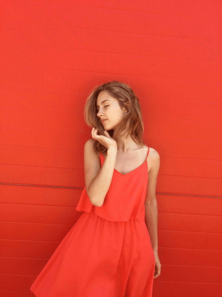 a picture of a lady in a red dress against a red wall.